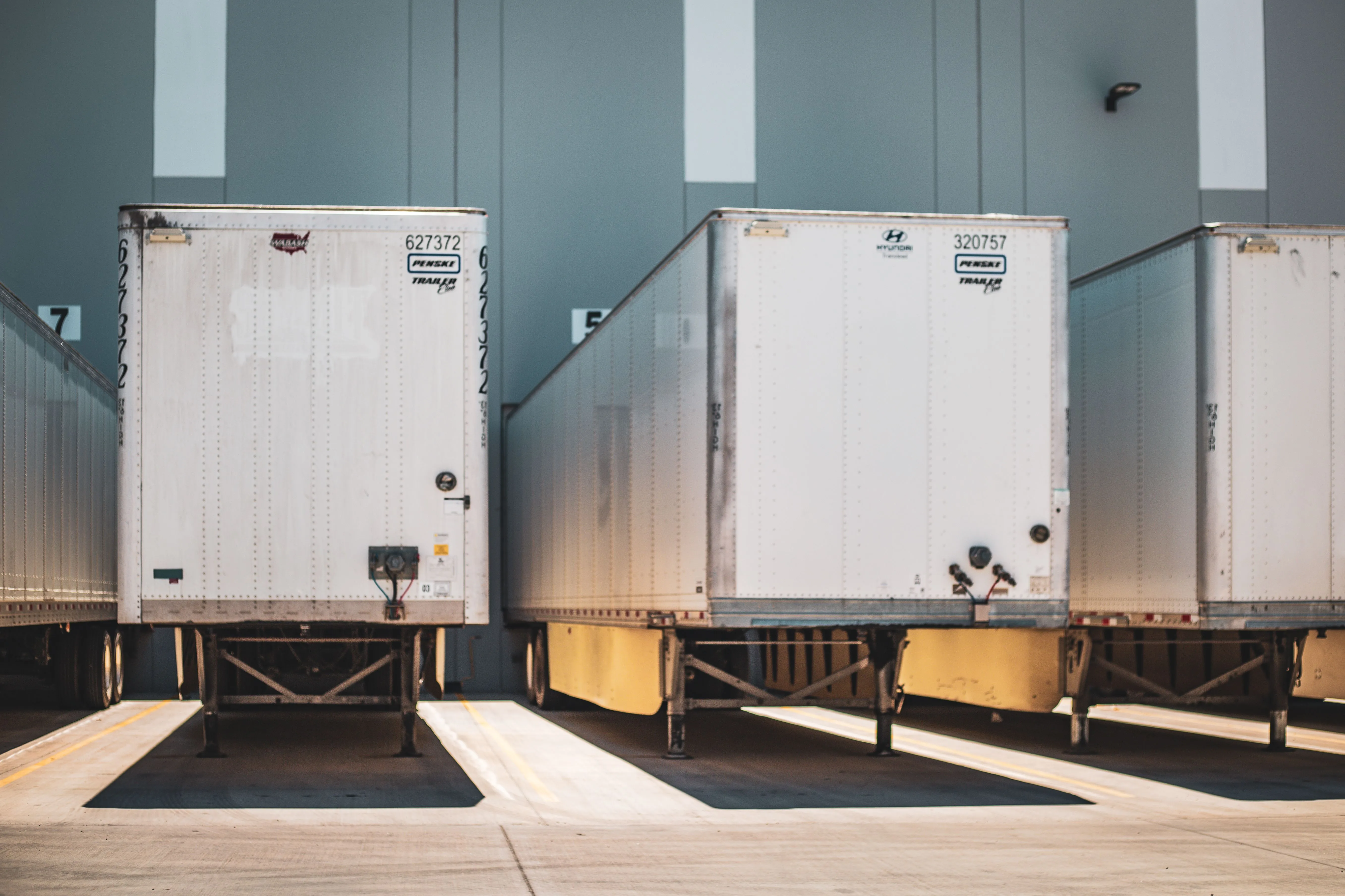 Freight trailers backed into numbered loading-dock bays at a distribution warehouse